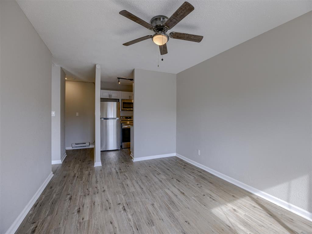 an empty living room with a ceiling fan