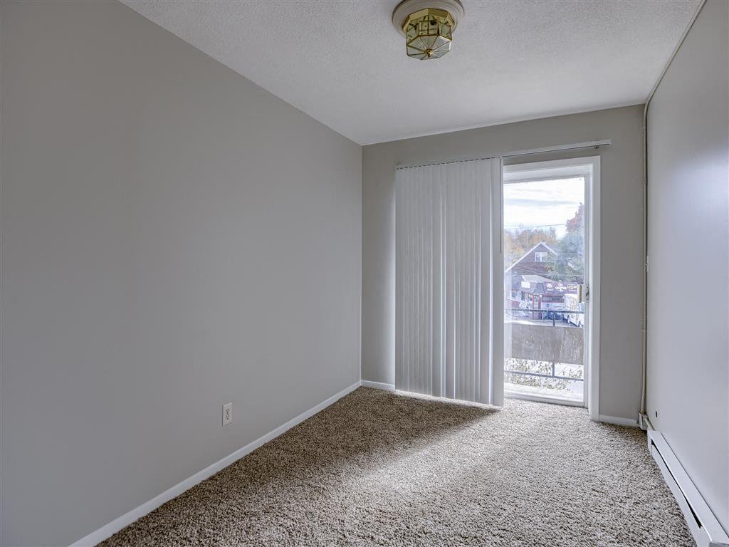 an empty bedroom with a sliding glass door to a balcony