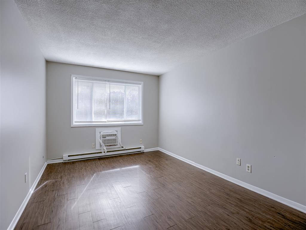 a bedroom with wood floors and a window