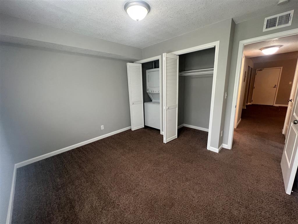 a bedroom with a stackable washer and dryer inside a small closet