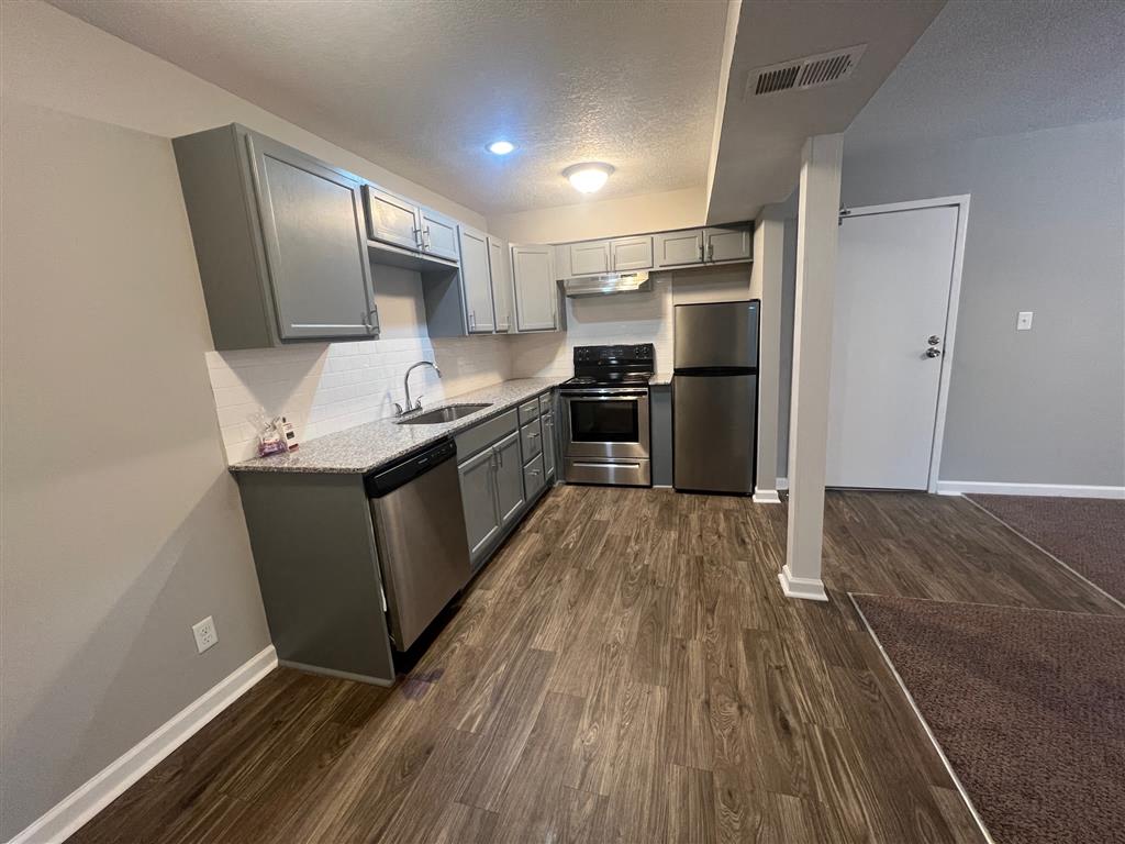 a kitchen with stainless steel appliances and a wood floor