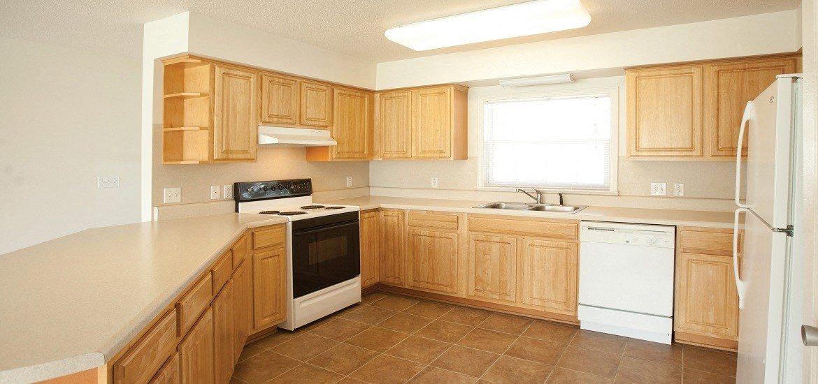 a kitchen with wooden cabinets and white appliances and a window