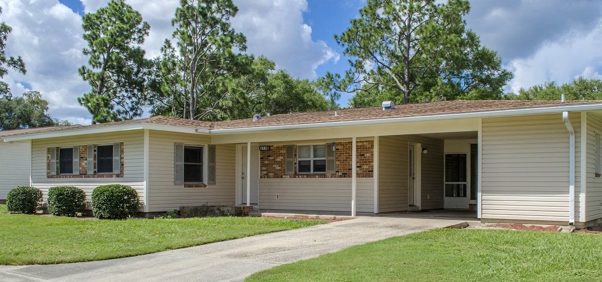 a white and brown house with a driveway and trees