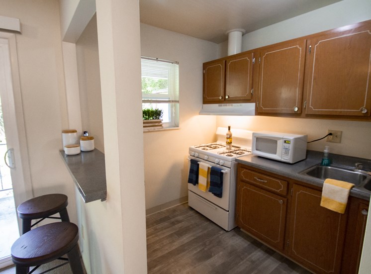 This is a photo of the kitchen of the 550 square foot 1 bedroom, balcony floor plan model apartment at College Woods Apartments in Cincinnati, OH.
