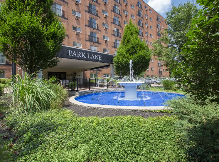 This is a photo of the building exterior featuring the fountain in front of the entrance to Park Lane Apartments in Cincinnati, OH.