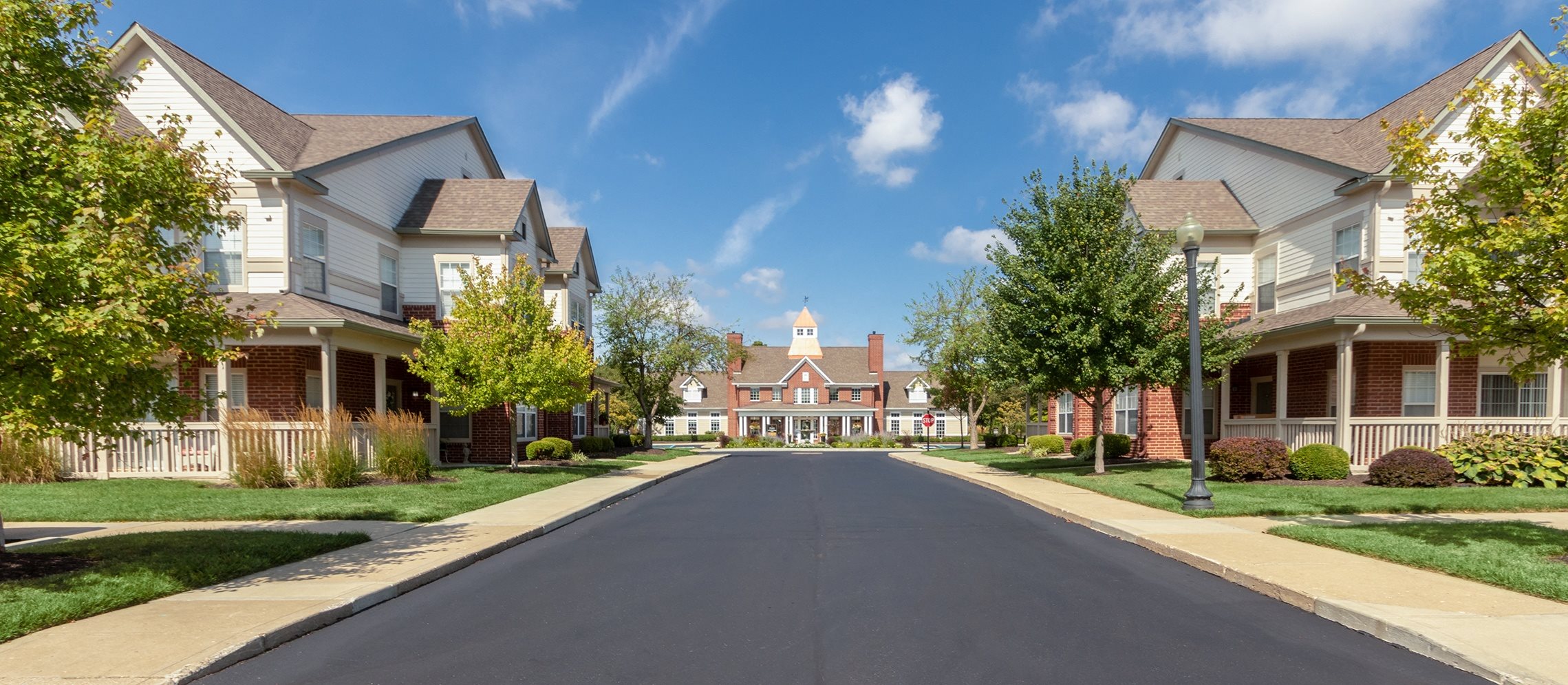 This is a photo of apartment exteriors from the road leading up to the Leasing Office at The Sanctuary at Fishers in Fishers, IN.