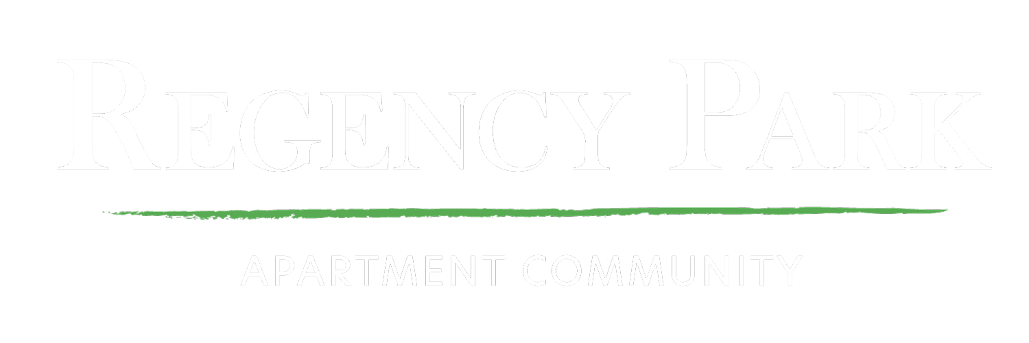 A black sign with white and green text that says "Regency Park Apartment Community".