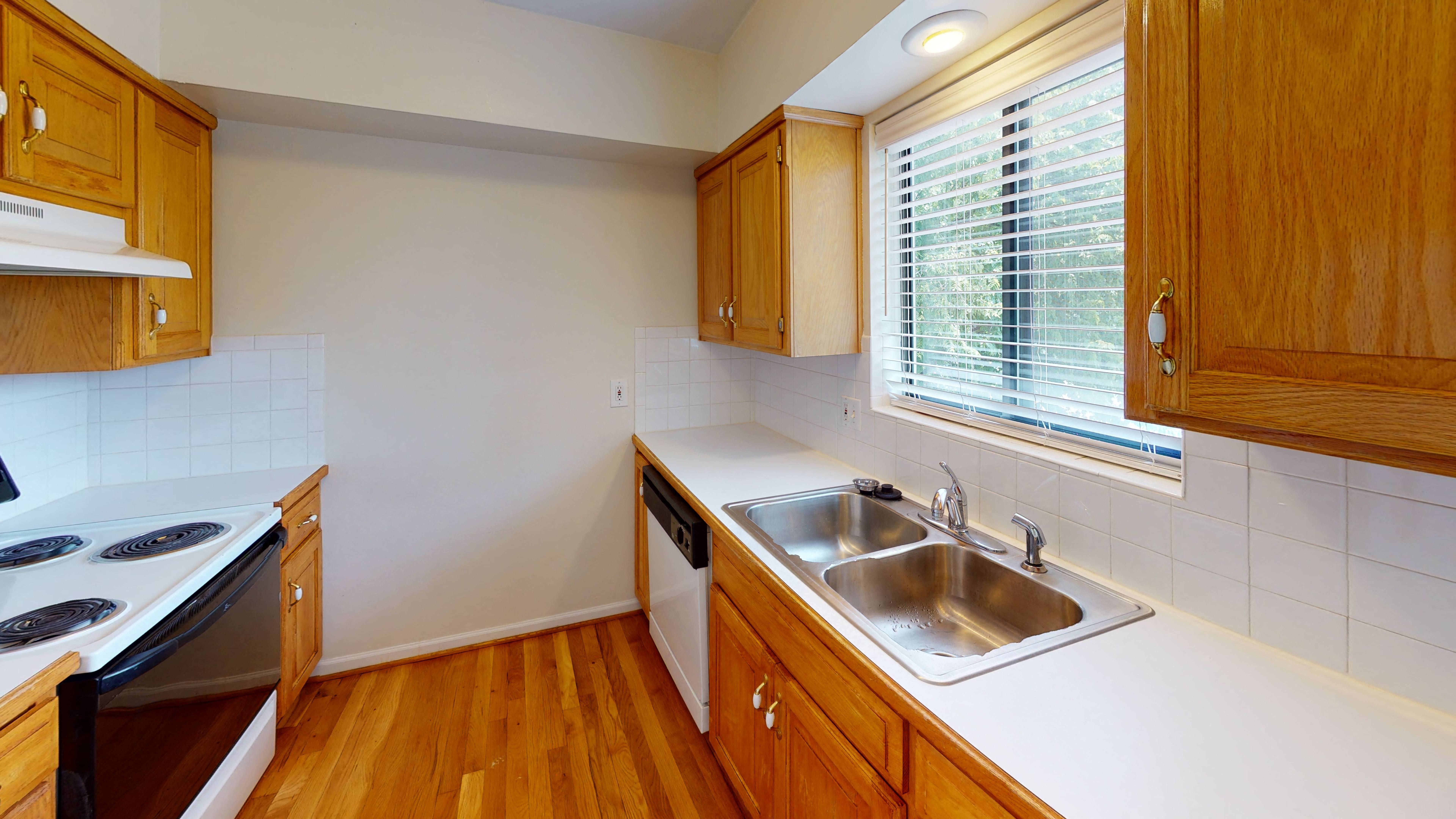 an empty kitchen with a sink and a window,an empty kitchen with a sink and a window