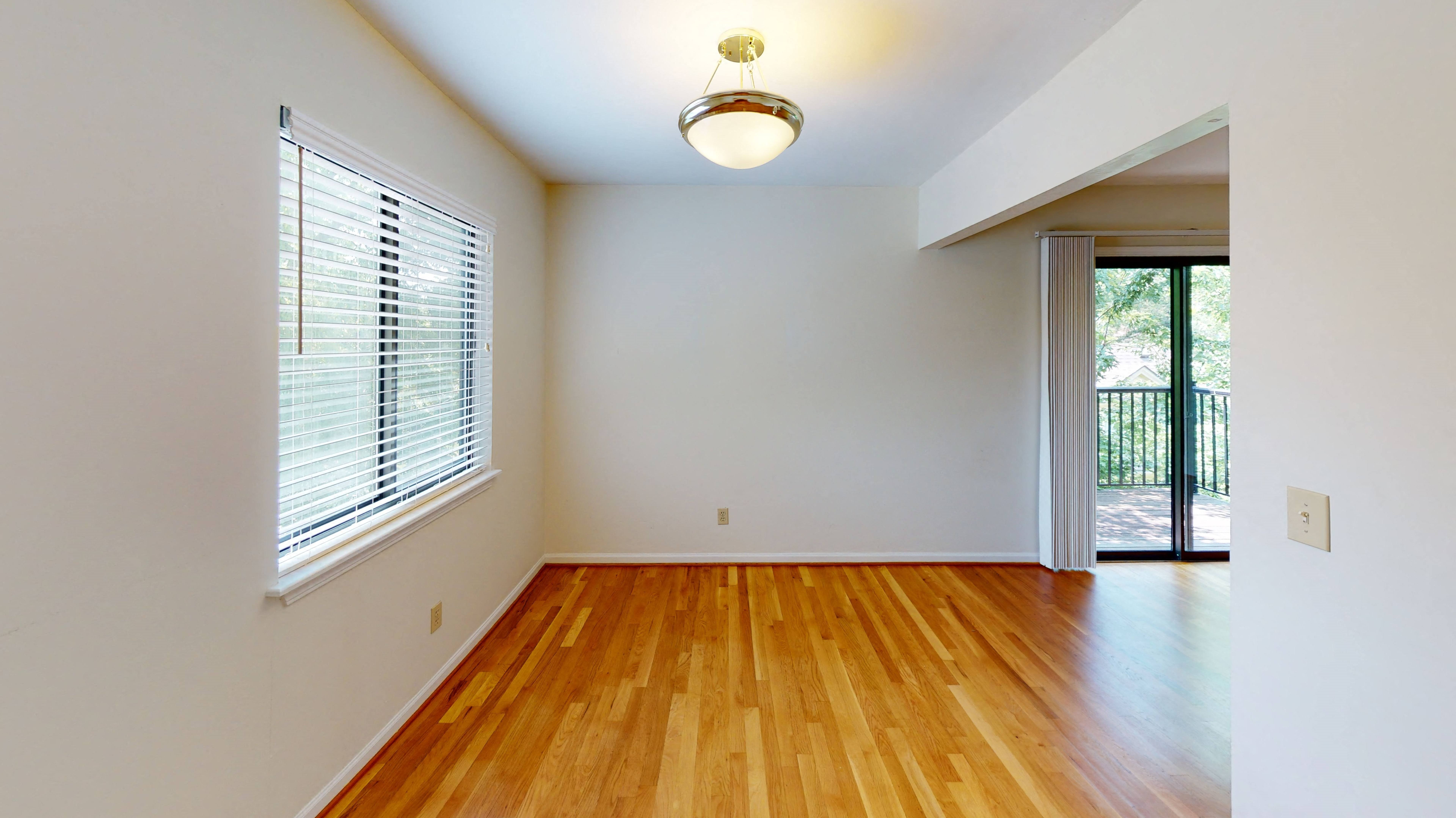 an empty living room with wood floors and a large window,an empty living room with wood floors and a large window,an empty living room with wood floors and a large window