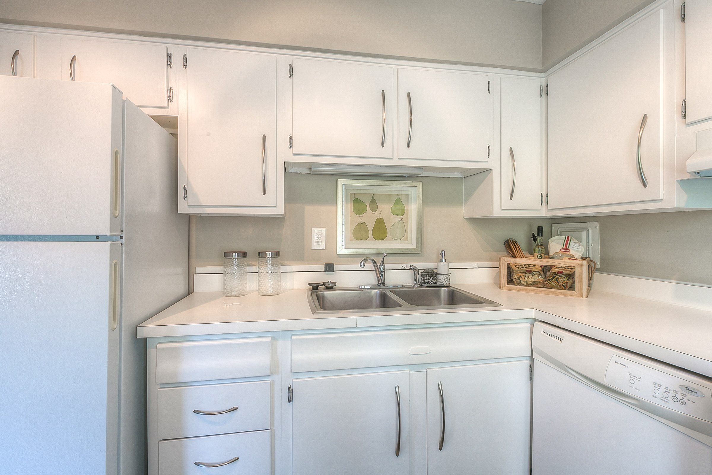 A white kitchen with a sink and a refrigerator.