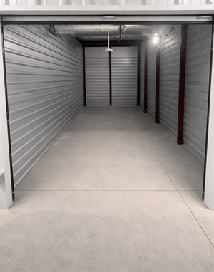 A long, narrow storage space with a concrete floor and walls covered in metal shelving.