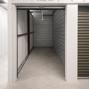 A storage unit with a closed grey shutter and a white door.
