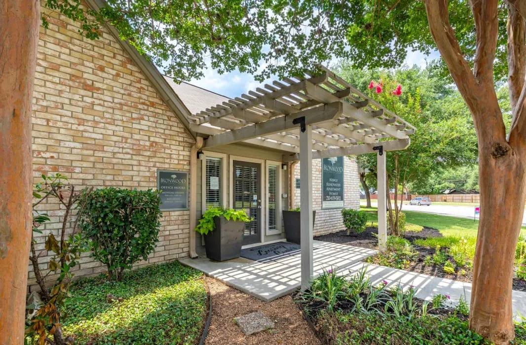 Office building entrance with pergola and garden beds at Peaks at Universal City Apartments, Universal City, TX