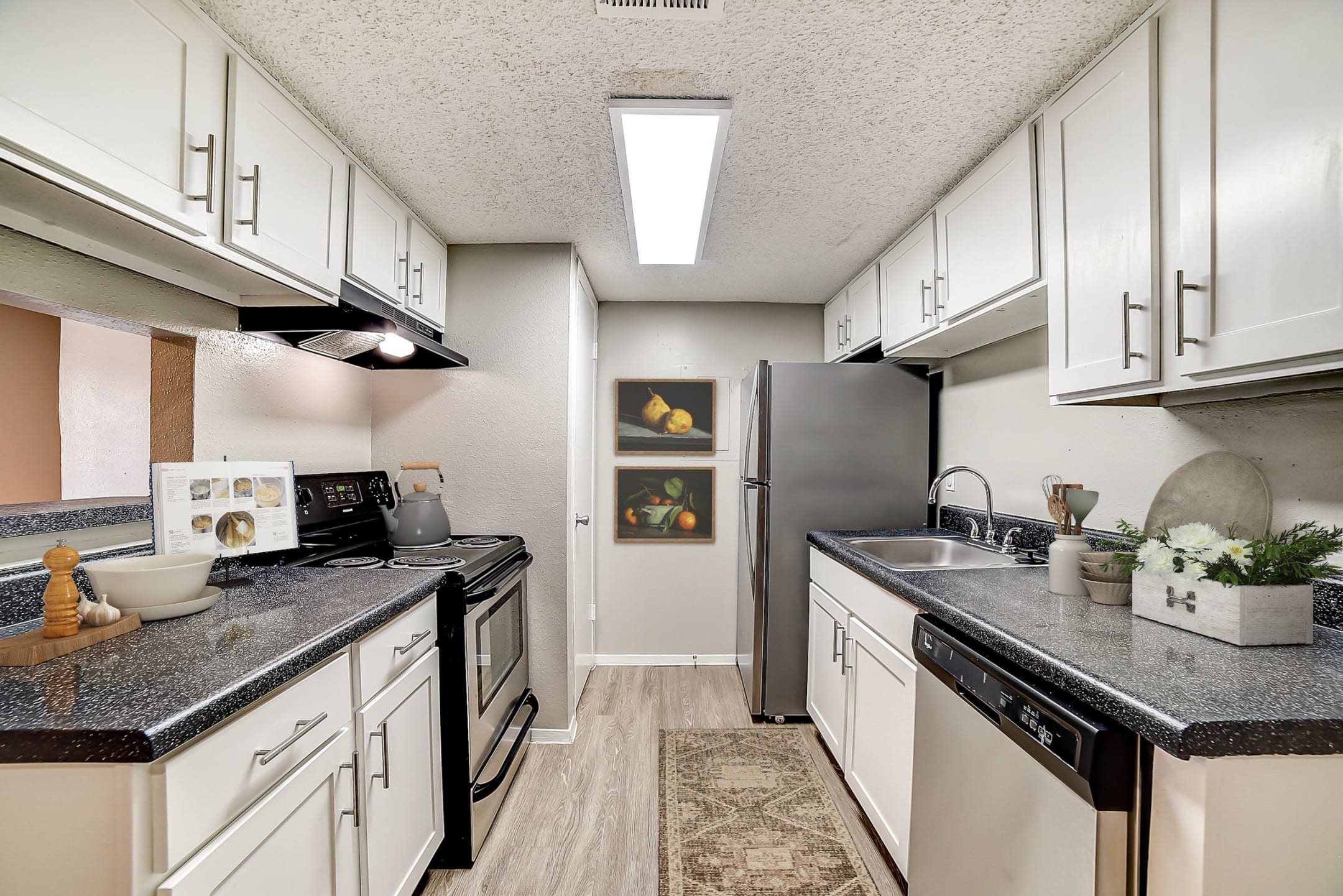 Galley kitchen with white cabinets and stainless steel appliances at Peaks at Universal City Apartments, Texas, 78148