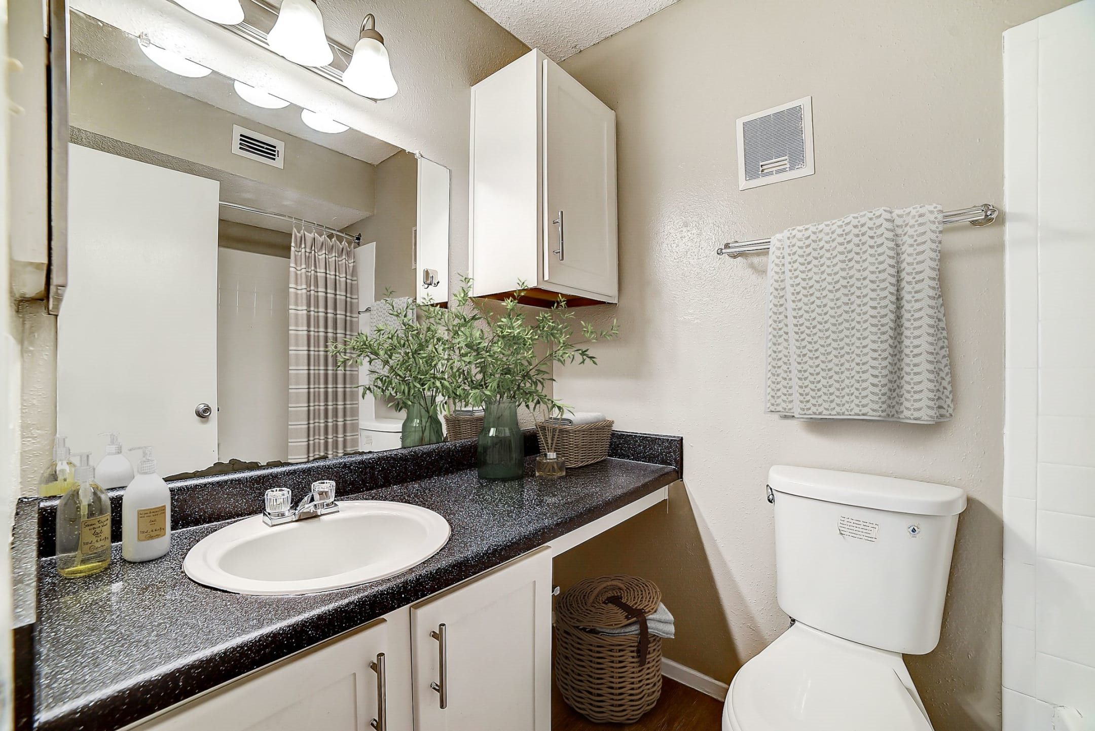 Bathroom with dark granite countertop and white cabinetry at Peaks at Universal City Apartments, Universal City, TX 78148