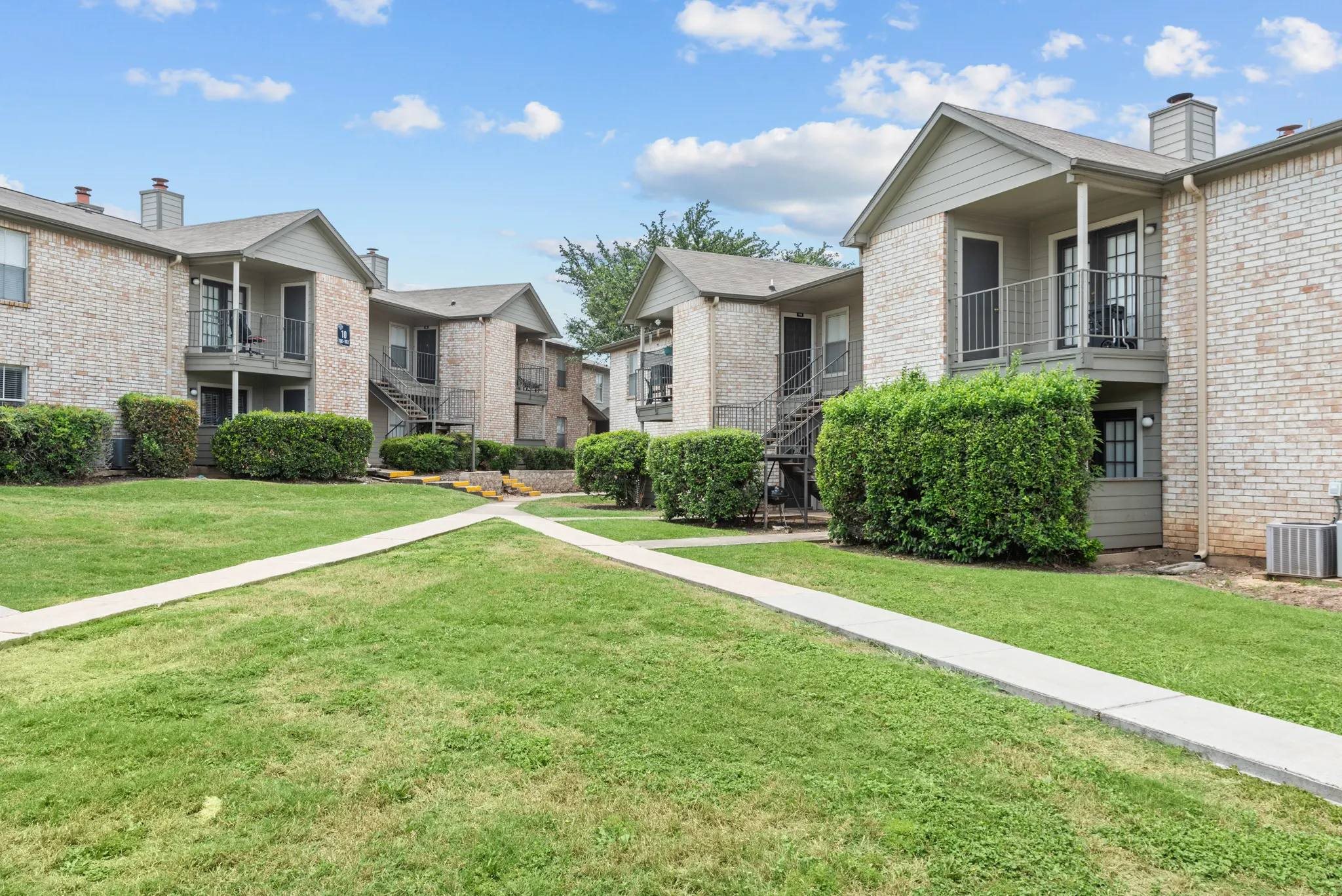 Courtyard with sidewalks and apartment buildings at Peaks at Universal City Apartments, Universal City, Texas