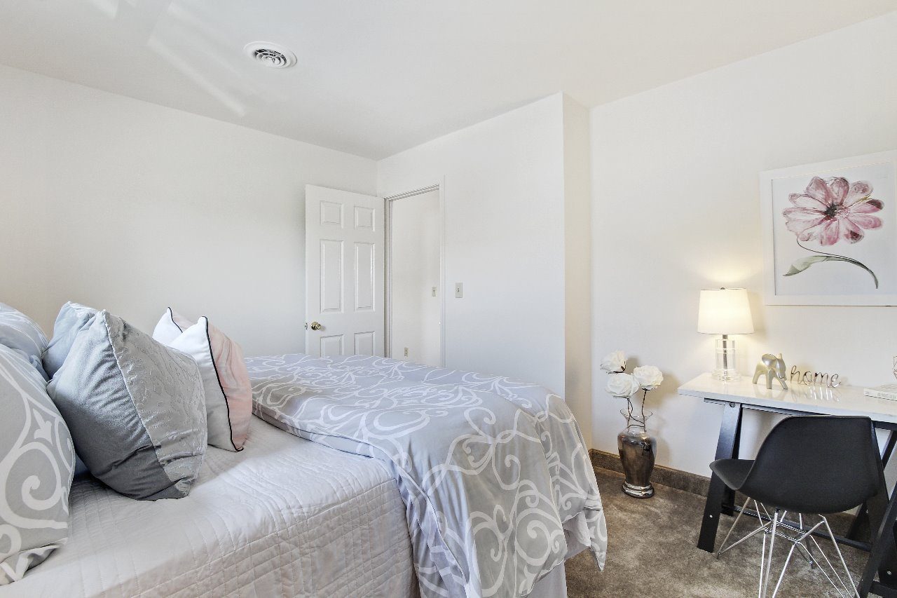 A dining room with a table set for two and a painting on the wall.