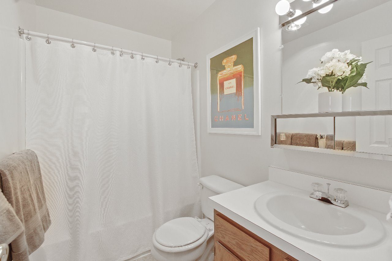 A dining room with a table set for two and a painting on the wall.