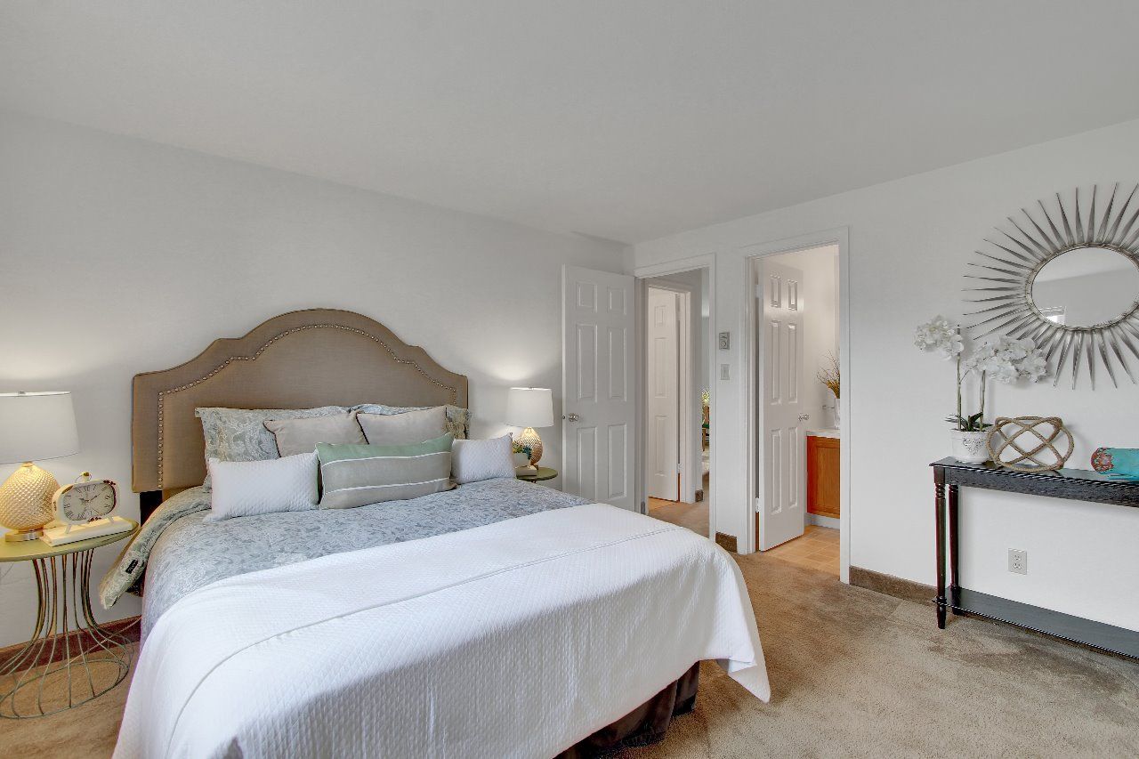 A bedroom with a large bed and a mirror on the wall.