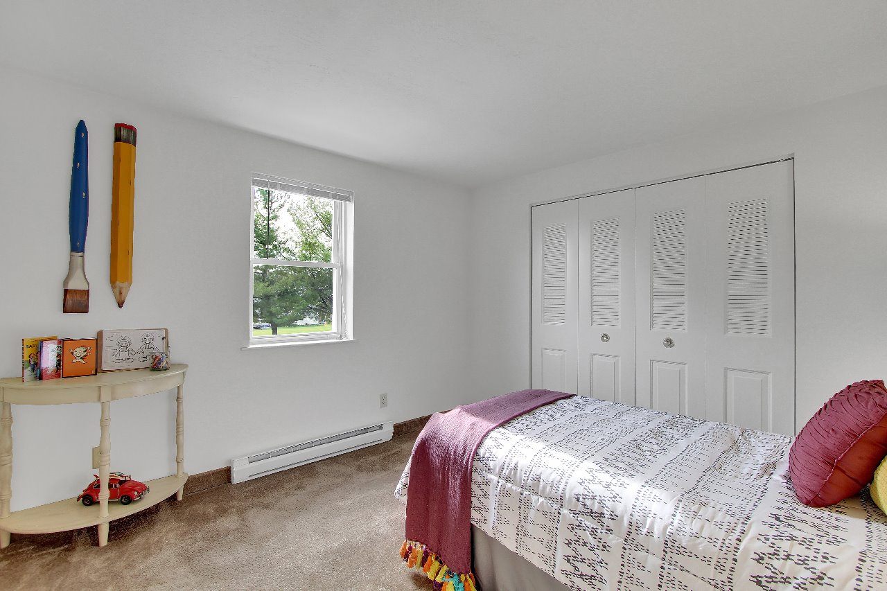 A bedroom with a bed, a window, and a dresser.