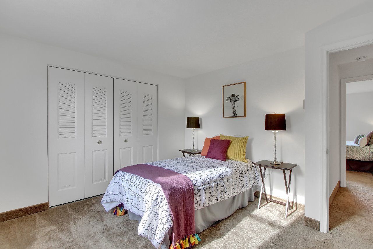 A bedroom with a bed, a table, and a painting on the wall.