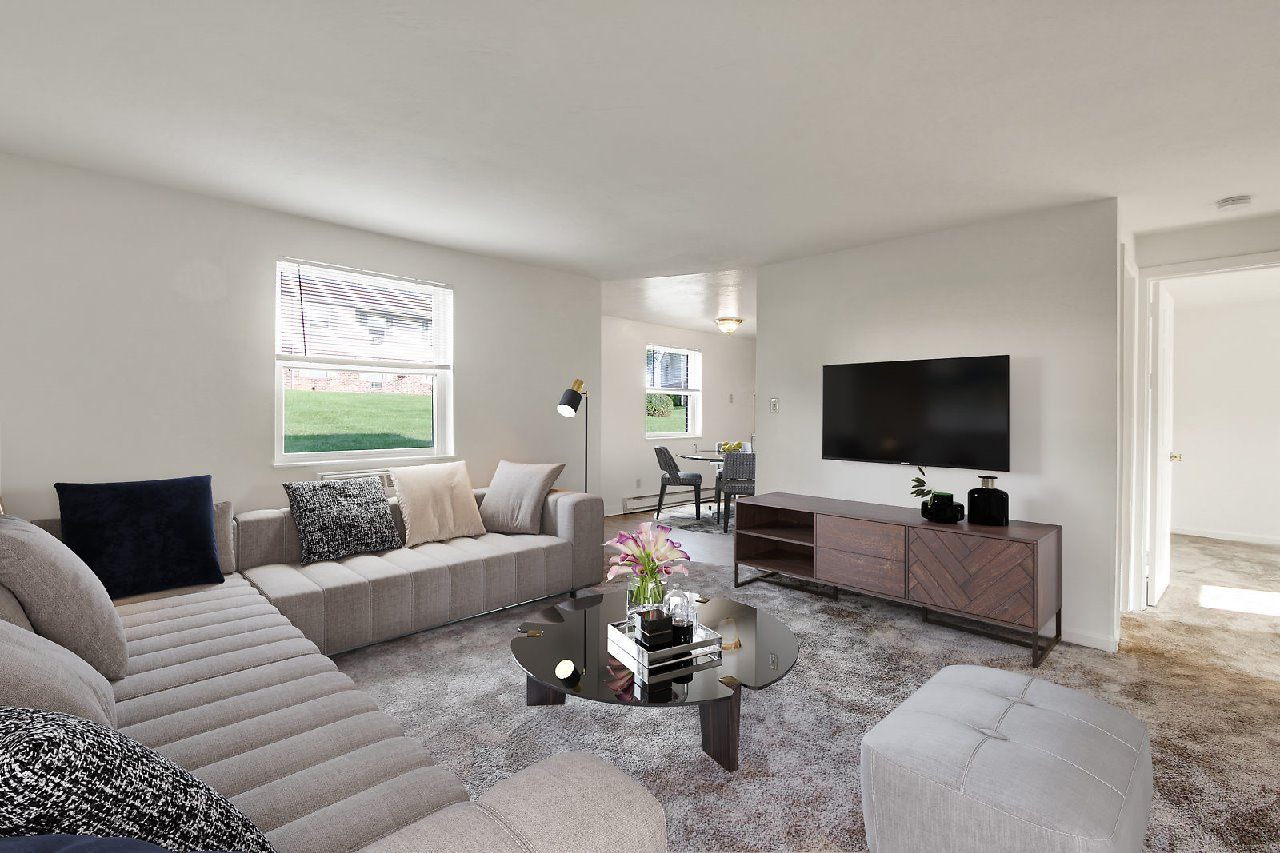A living room with a grey couch, a coffee table, and a flat screen TV.