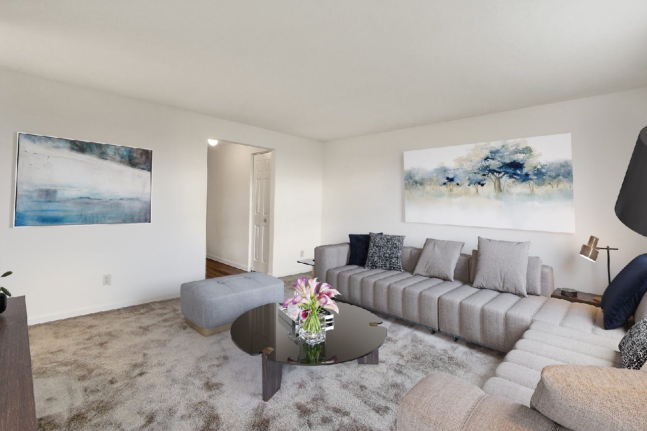 A living room with a grey couch and a coffee table with flowers on it.