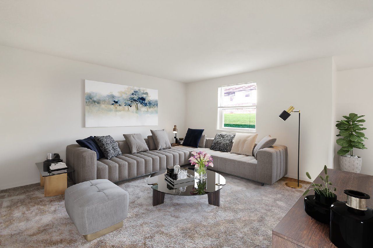 A living room with a grey sofa, a coffee table, and a painting on the wall.