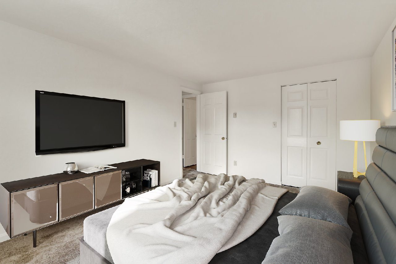 A modern bedroom with a large bed and a flat screen TV mounted on the wall.