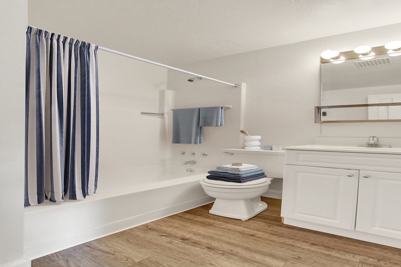 A white bathroom with a toilet, sink, and striped curtains.