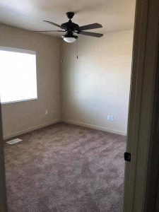 an empty room with a ceiling fan and a window