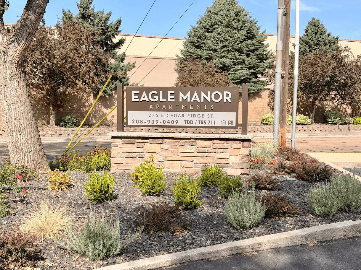A sign for Eagle Manor Apartments is displayed in front of a building.