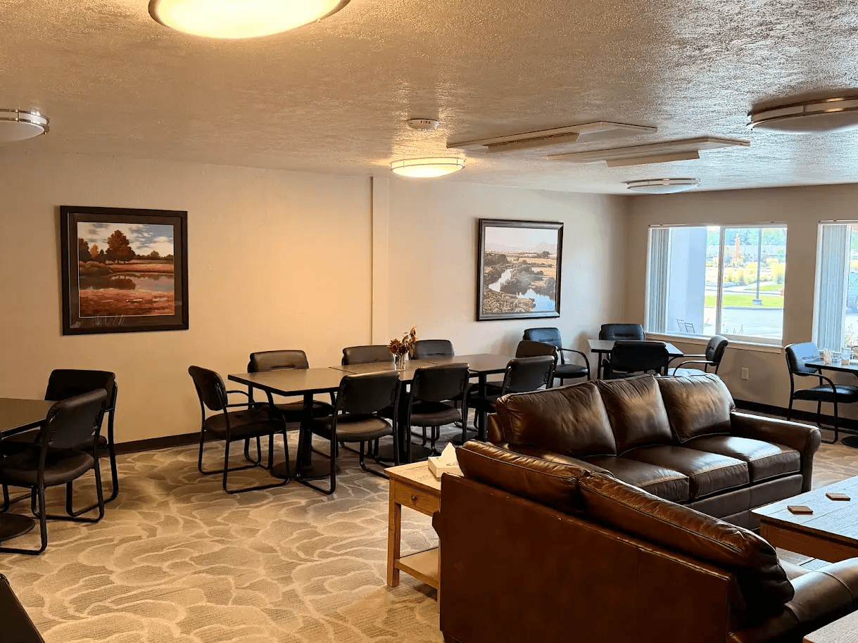 A living room with a couch, chairs, and two pictures on the wall.