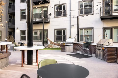 A patio with a table and chairs is surrounded by apartment buildings.