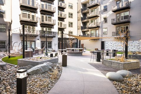 A modern courtyard with a paved walkway, seating areas, and a small garden.