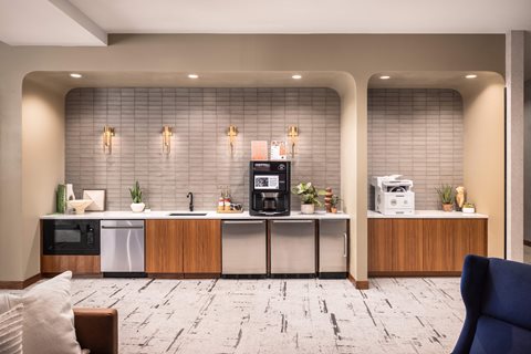 A modern kitchen area with a sink, microwave, and coffee machine.