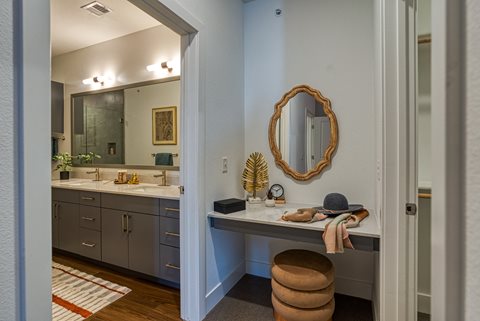 a bathroom with a vanity with a stool and a mirror on the wall