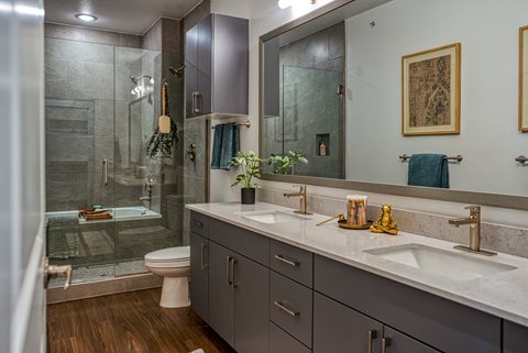 a bathroom with gray cabinets and a glass shower