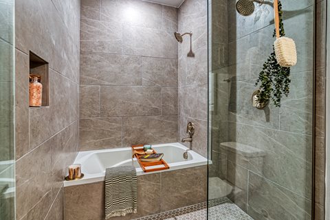 a bathroom with gray tiles and a glass shower door