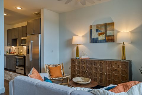 a living room with a couch and chair and a kitchen in the background