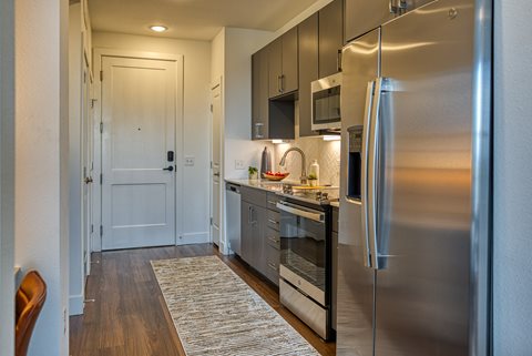 a kitchen with gray cabinets and stainless steel appliances
