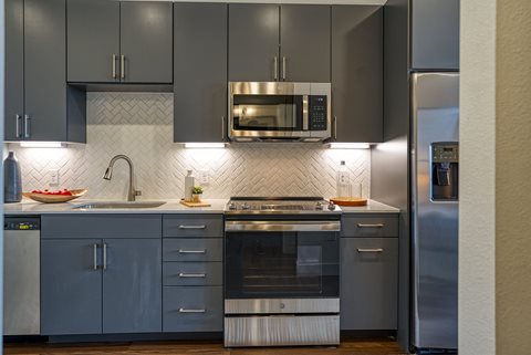 a kitchen with gray cabinets and stainless steel appliances