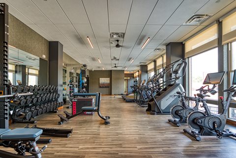 a large fitness room with cardio equipment and weights