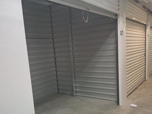 A storage unit with a grey shutter door and a white door.