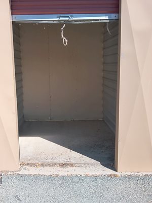 A small, empty room with a red door and a white wall.