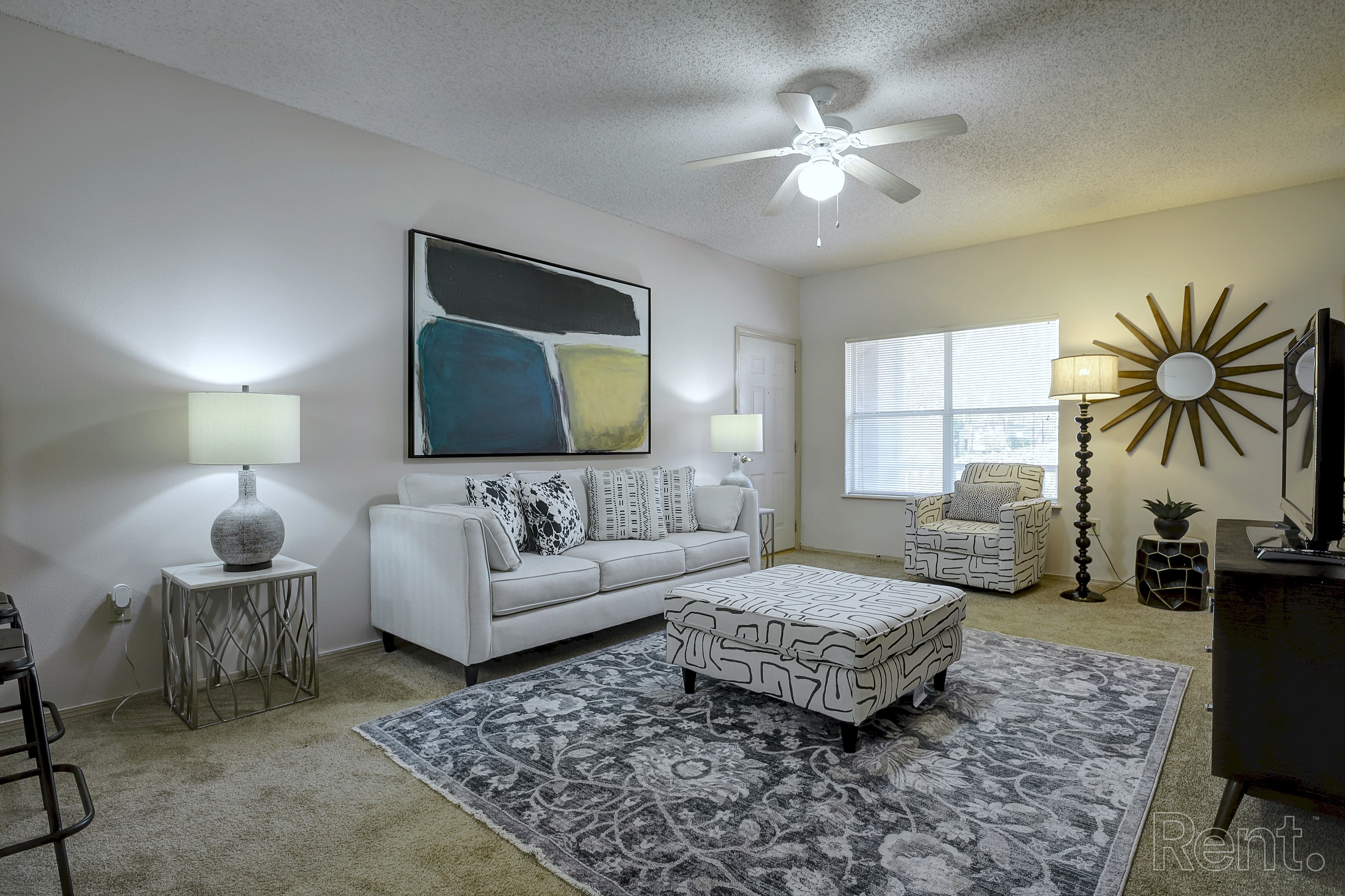 A living room with a white couch, a rug, and a ceiling fan.