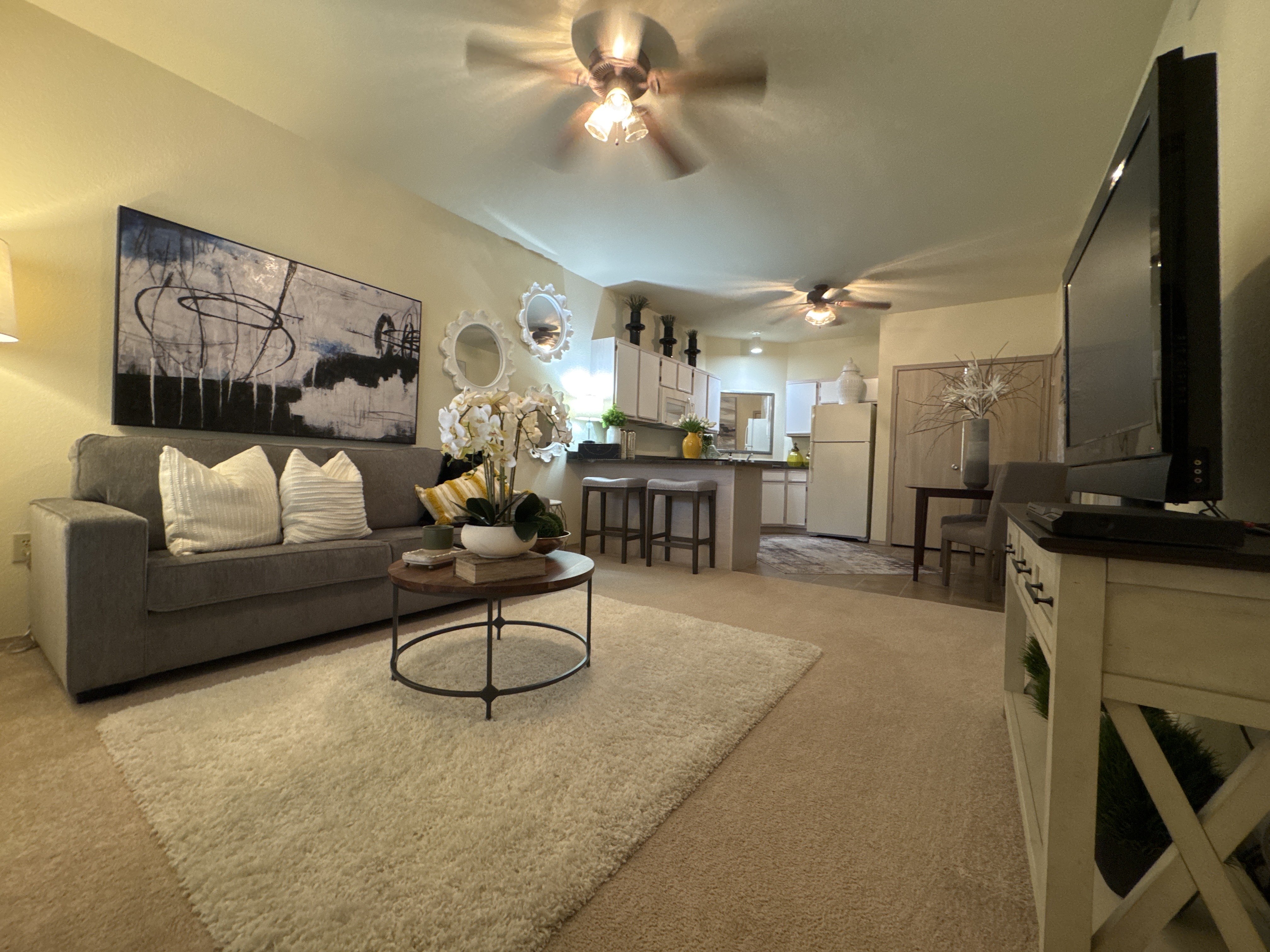 A living room with a grey couch, a coffee table, and a ceiling fan.