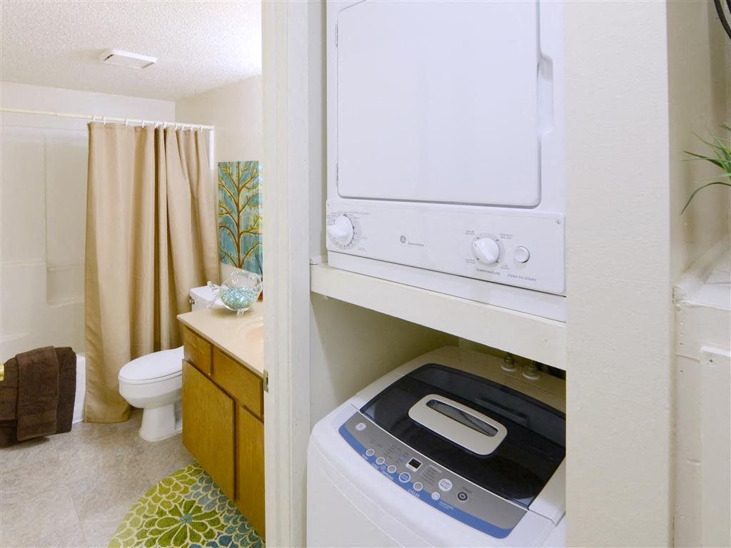 a white washer and dryer in a bathroom with a toilet