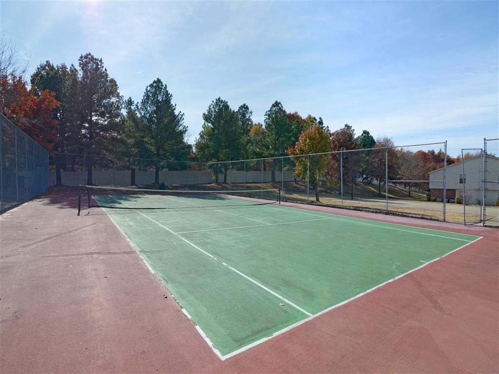 a tennis court with green and red turf and a fence