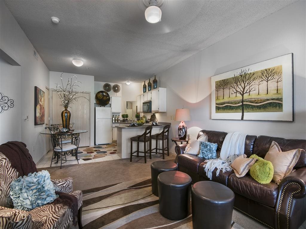 A living room with a brown leather couch and a painting on the wall.